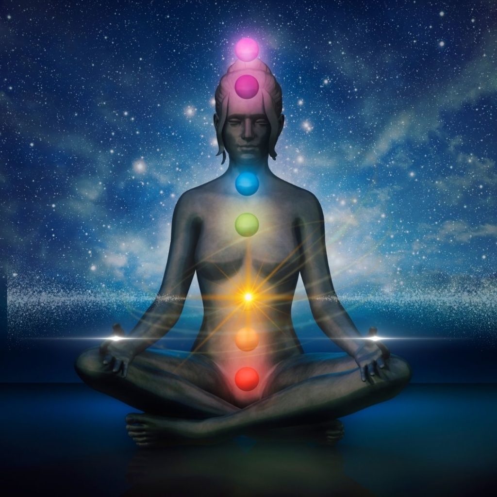 someone sitting in lotus position with chakraas glowing different colours